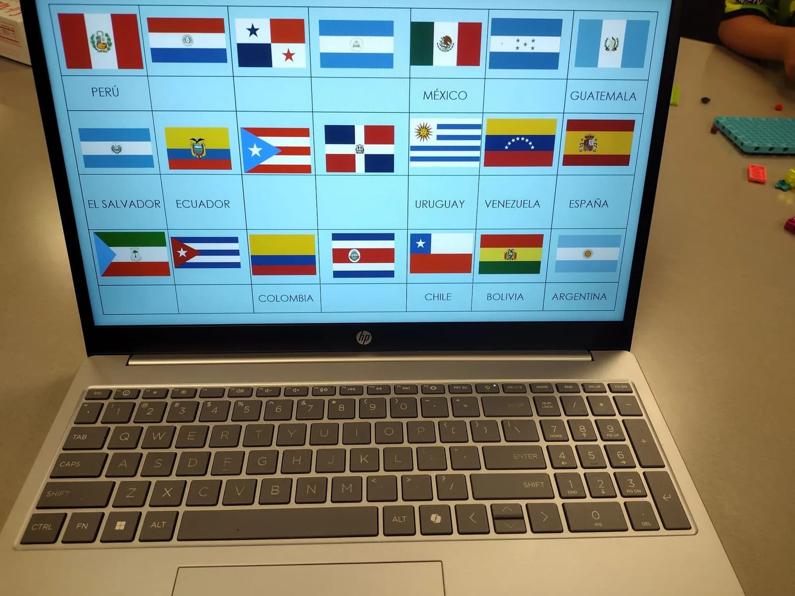 A laptop screen showing a grid of flags of Spanish-speaking countries with their names
